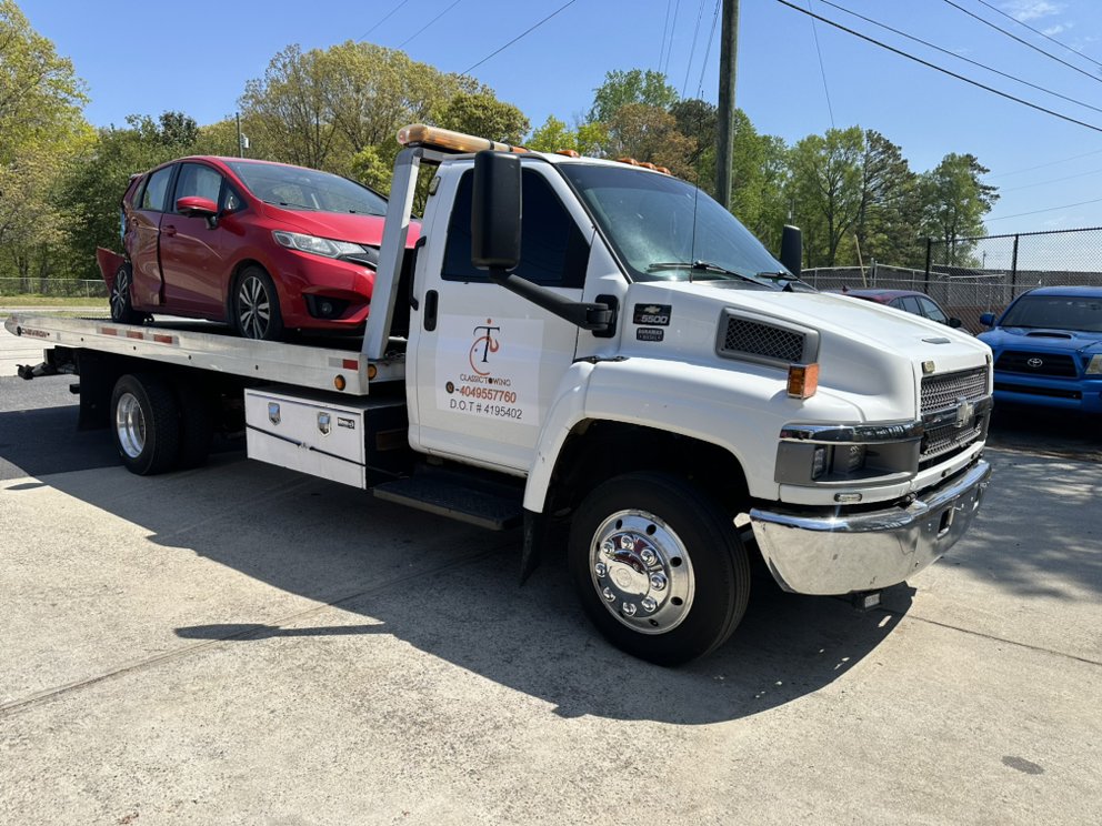 Classic Towing flatbed tow truck loaded with a red Honda Fit in McDonough, Georgia